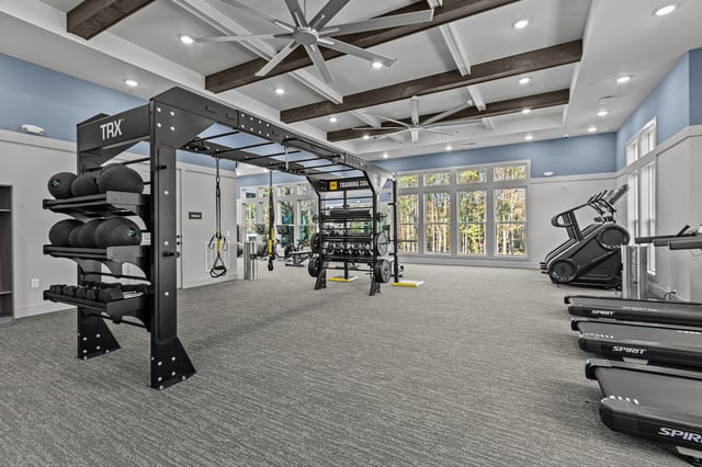 Fitness center with treadmills, stair climbers, free weights, and a TRX training rig.