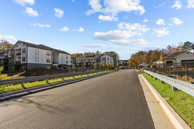 Street view of a modern apartment complex with white and dark gray buildings.