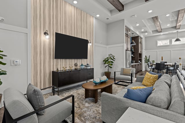 Modern living room with a sectional sofa, accent chairs, coffee table, and a wall-mounted TV.
