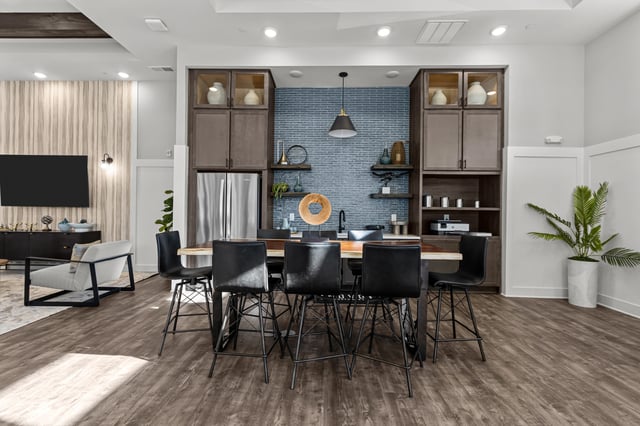 Community kitchen area with large island and seating, stainless steel appliances and modern decor.