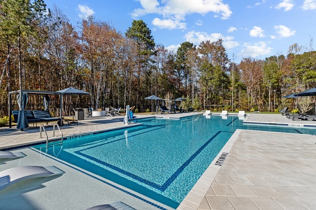 Luxury swimming pool with lounge chairs and cabanas on a sunny day.