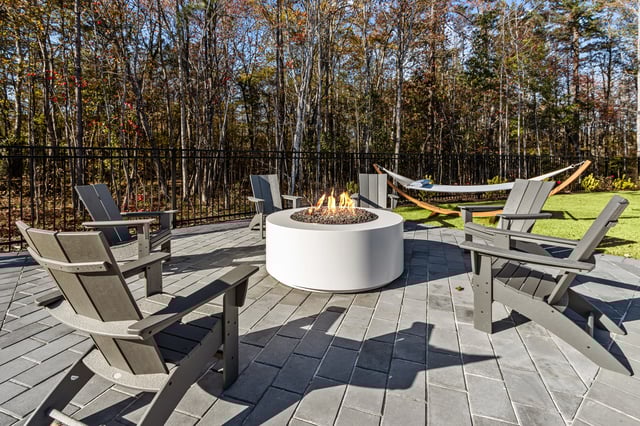 Outdoor patio with a fire pit, chairs, and a hammock.