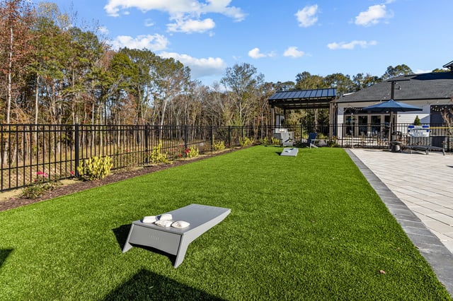 Outdoor lounge area with cornhole game and seating.