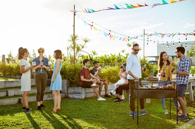 People enjoying an outdoor BBQ party with drinks and music.