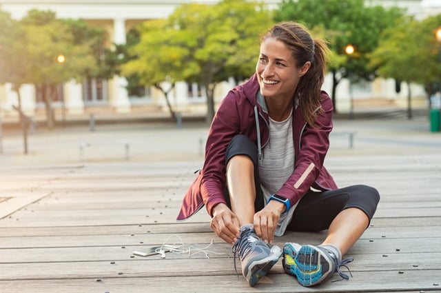 Woman tying her running shoes outdoors.