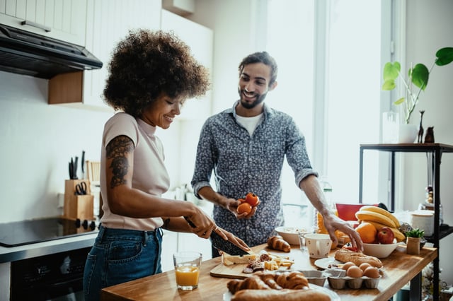 A couple prepares breakfast together in a bright, modern kitchen.