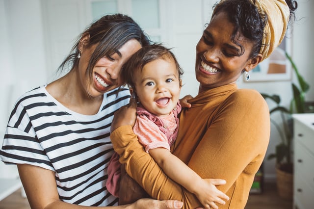 Two women smiling and holding a baby