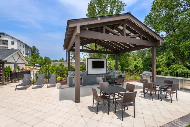 Outdoor covered patio with seating, tables, television, and grills.