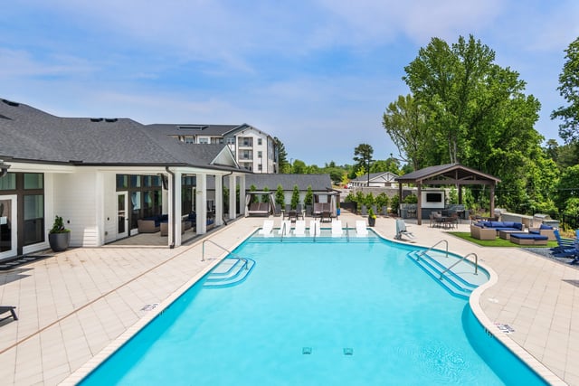 Outdoor swimming pool with lounge chairs, cabanas, and an outdoor kitchen.