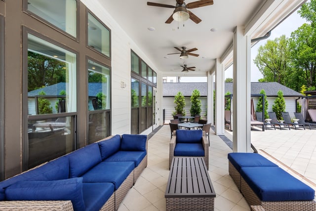 Outdoor covered patio area with blue sectional sofa, coffee table, and chairs.