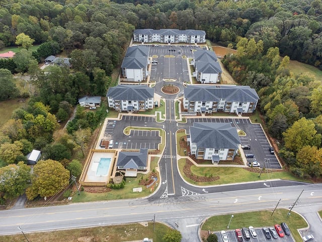 Aerial view of apartment buildings, parking lots, and an outdoor swimming pool.