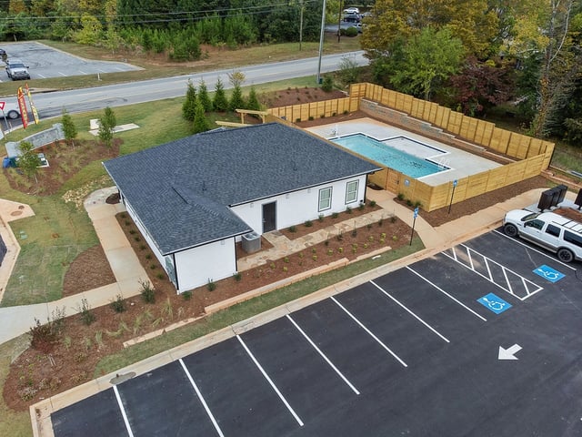 Exterior view of a building with a swimming pool and parking lot