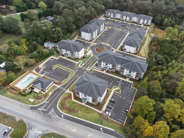Aerial view of apartment buildings, parking lots, and a swimming pool.