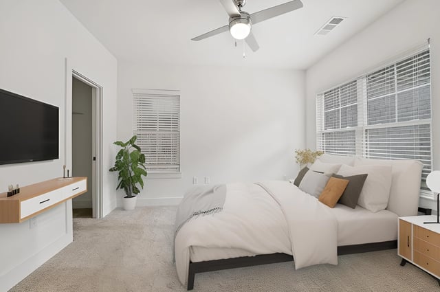 Modern bedroom with a king-size bed, mounted TV, and large windows.