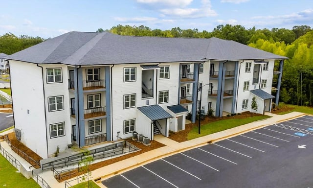 Exterior view of the apartment building with a parking lot in front.