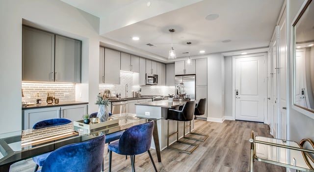 Modern kitchen and dining area with sleek gray cabinetry, stainless steel appliances, and a large island with bar stools.
