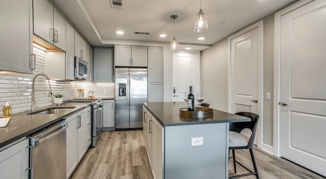 Modern kitchen with stainless steel appliances, gray cabinets, and a center island.