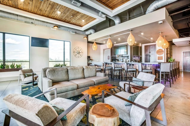 Comfortable seating area with sofas, chairs, a live-edge wood coffee table, and a bar with stools.