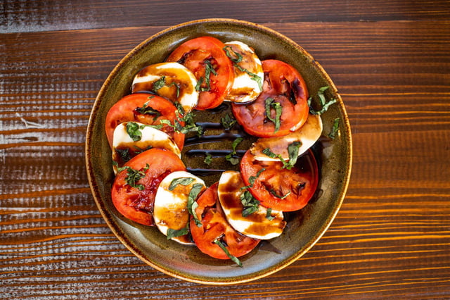 Caprese salad with tomatoes, mozzarella, and basil on a plate.