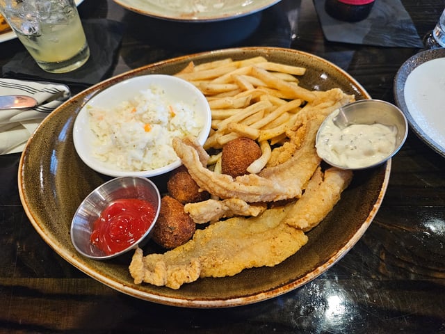 Fried fish, french fries, coleslaw, hushpuppies, and tartar sauce.