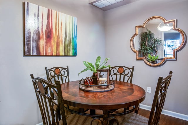 Dining area with a round table, ornate chairs, and abstract wall art.