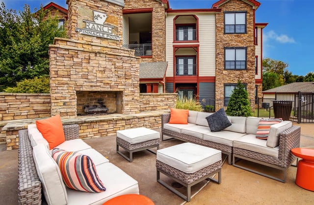 Outdoor living space with a stone fireplace and comfortable seating area.