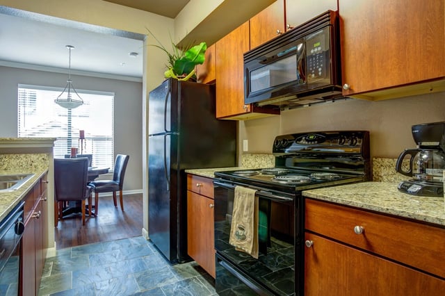Kitchen with black appliances, granite countertops, and wood cabinets.