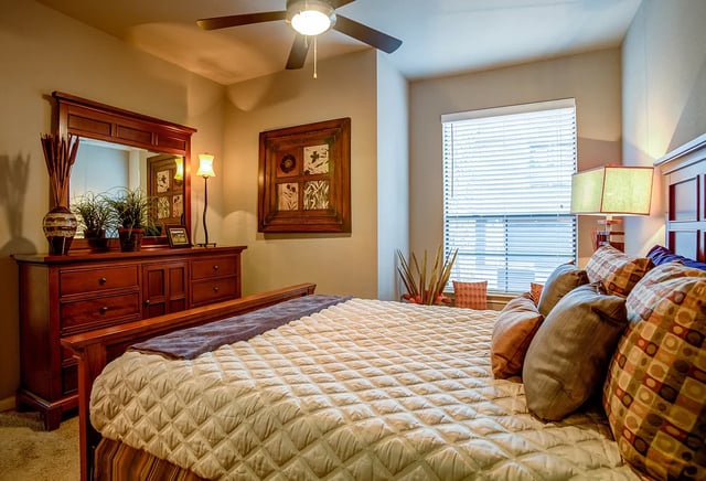 Bedroom with a large bed, dresser, and window.