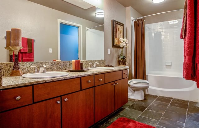 Bathroom with double vanity, large mirror, toilet, and bathtub.