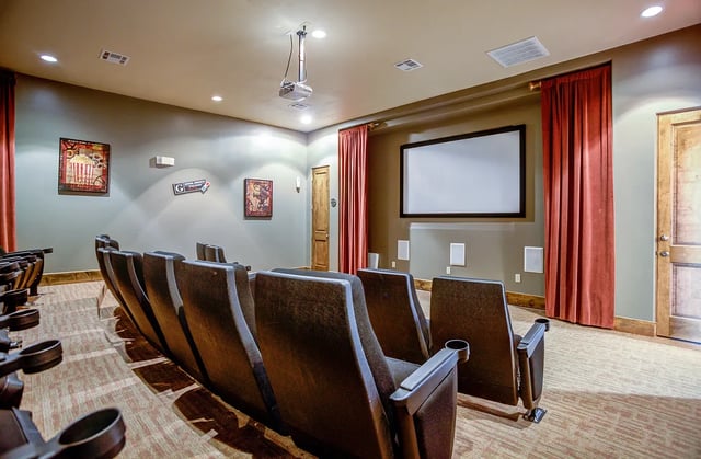 Theater room with rows of comfortable seats facing a large projector screen.