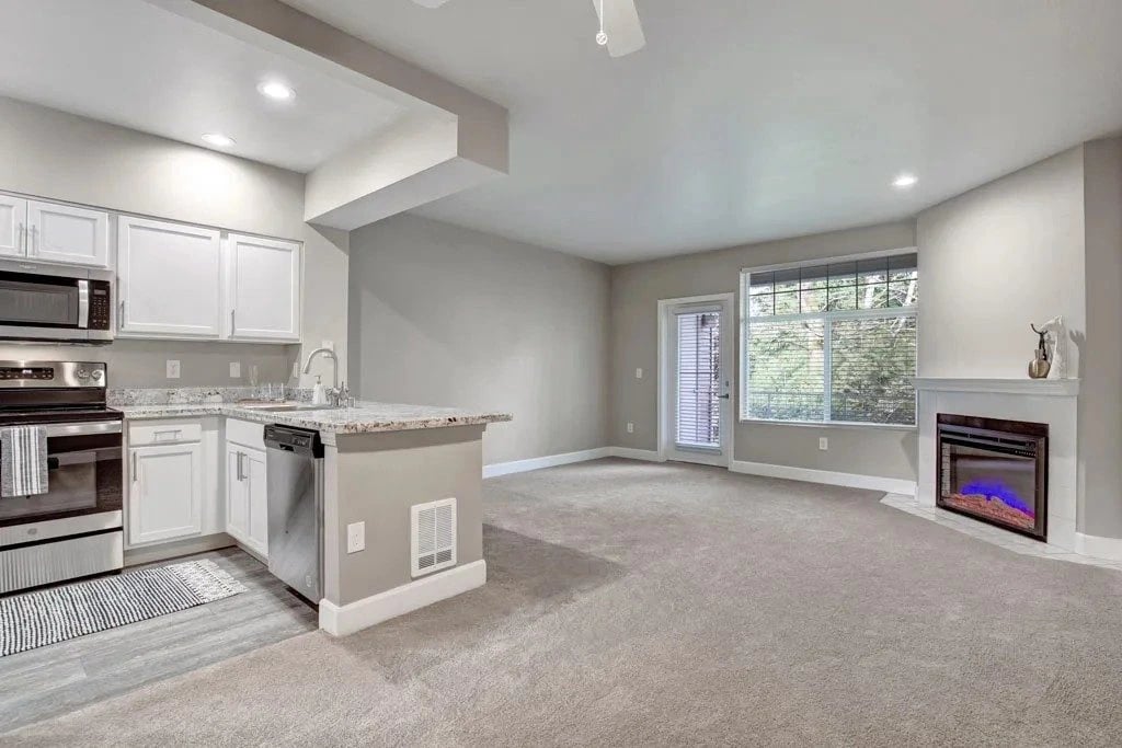 Open-concept living area with a kitchen, granite countertops, and a fireplace.