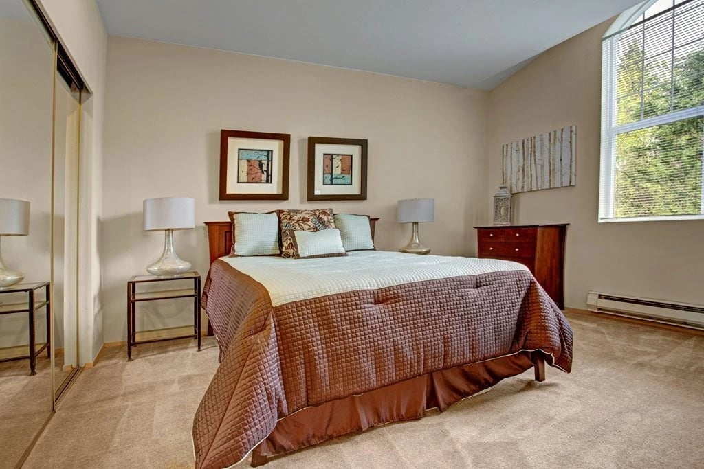 Bedroom with a queen bed, two nightstands, lamps, dresser, and a window.