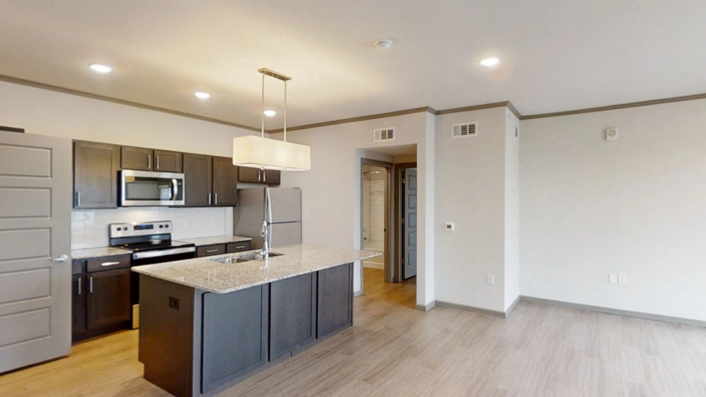 Open-concept apartment kitchen with island and stainless steel appliances.