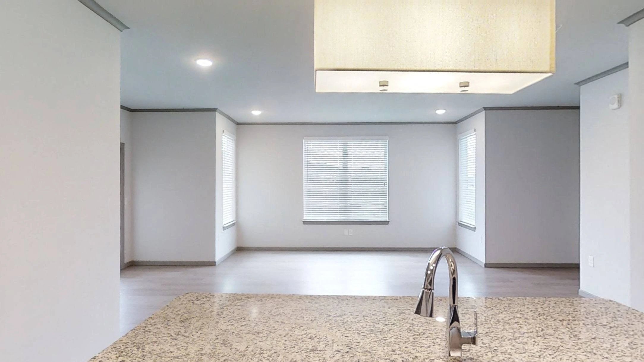 Kitchen island with granite countertop and sink in an empty apartment living area.