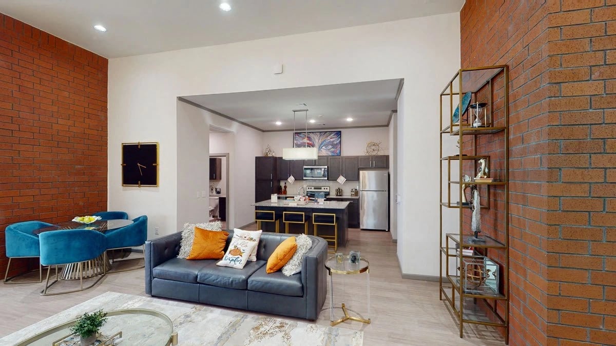 Open-concept living area and kitchen in a modern apartment with brick accent walls.