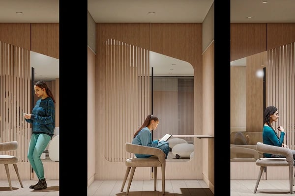 Woman sits and reads in a modern lounge with wood slat partitions.